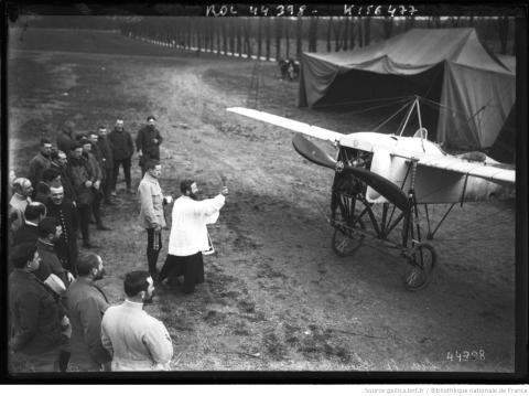 Sur le front, bénédiction d&#039;un Blériot, prêtre bénissant un avion entouré de soldats. Agence Rol, 1915 - source : Gallca-BnF